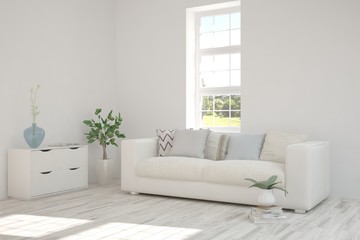 White room with sofa and green landscape in window. Scandinavian interior design