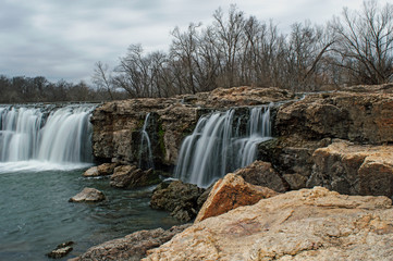 Fototapeta premium Waterfall among boulders on a warm winter day makes a scenic view