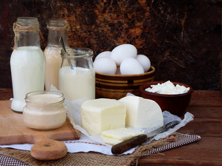 Set of fresh dairy products on wooden background: milk, cheese, cottage, yogurt, egg, mozzarella, ryazhenka, feta.