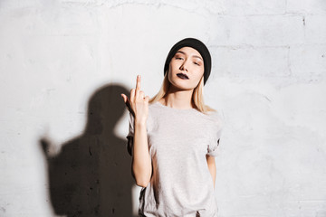 Stylish woman with black lipstick standing and showing middle finger