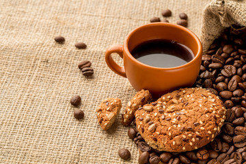 Black coffee with a oatmeal cookies on burlap background
