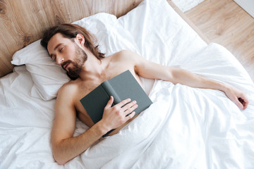 Exhausted man with book lying and sleeping in bed