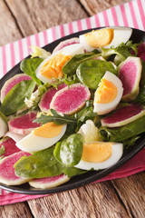 salad of watermelon radishes, eggs, spinach and lettuce mix close-up. vertical