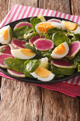 Healthy salad with radishes, eggs, spinach and lettuce mix close-up. vertical