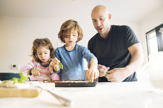 Father preparing food with children at table in home
