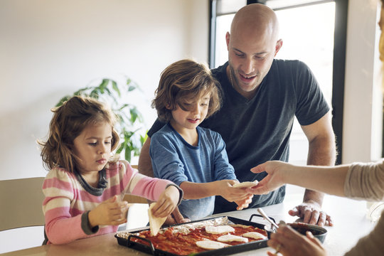 Family preparing food at table in home