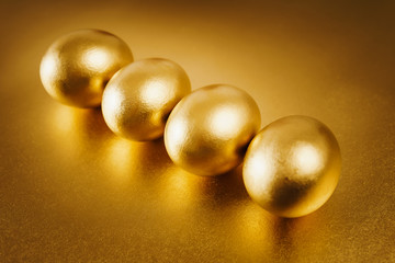 four gold Easter eggs on a shiny background