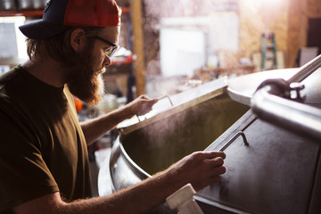 Brewer looking in machinery at brewery