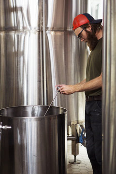 Brewer using thermometer while working at brewery