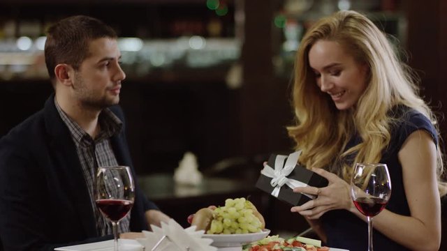 young woman getting a present from man