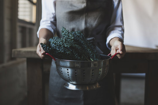Midsection of woman holding kale in colander