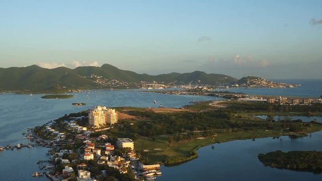 St Maartin Aerial v1 Flying low over lagoon panning with airport and golf course views at sunset.