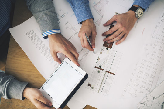 Cropped image of businessmen analyzing blueprints in office