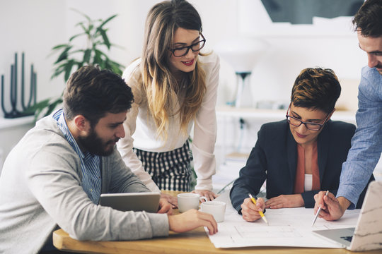 Business People Discussing Blueprints In Office