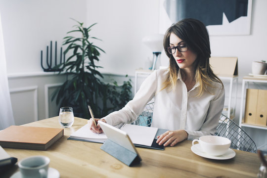 Businesswoman Writing While Sitting At Desk In Office