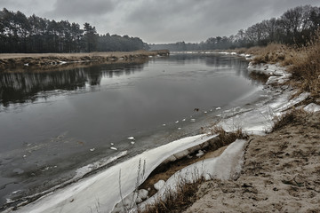 Icy river Warta banks during winter in Poland.
