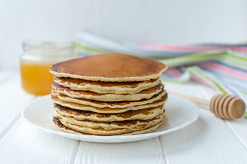 Healthy breakfast. Stack of delicious, homemade pancakes with honey, cherry and banana on white plate 