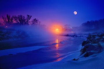 In freezing winter night full moon illuminates the river is covered with with ice, snow and fog.