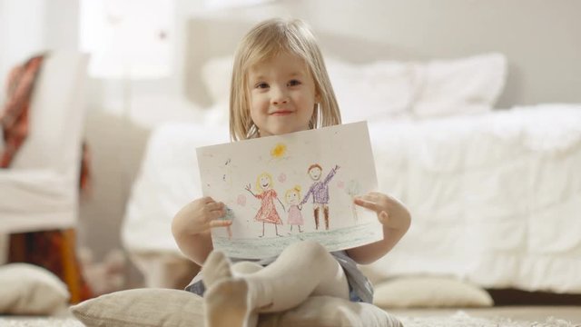 Cute Young Girl Sitting on Pillows Shows Drawing of Her Family. Shot on RED EPIC-W 8K Helium Cinema Camera.