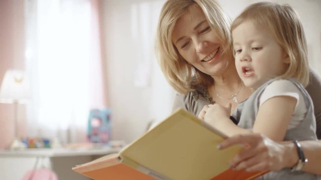 Cute Little Girl Sits on Her Grandmother's Lap and They Read Children's Book. Slow Motion. Shot on RED EPIC-W 8K Helium Cinema Camera.