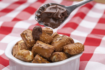 Putting chocolate on pretzels.