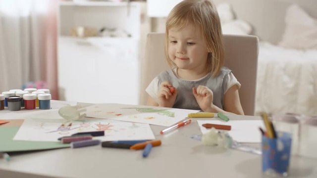 Cute Little Girl Sits at Her Table and Draws with Crayons. Happy with the Results She Smiles.Her Room Is Pink, Pretty Drawings Hanging on the Walls. Shot on RED EPIC-W 8K Helium Cinema Camera.