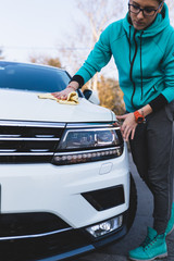 A woman cleaning car with microfiber cloth, car detailing (or valeting) concept. Selective focus. 