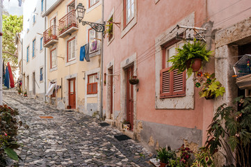 Typical narrow street and cobblestone floor of Alfama district in Lisbon, capital of Portugal