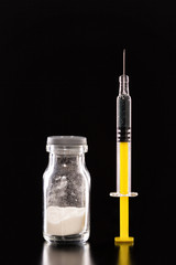 Syringe and medical vial, upright standing, isolated on black background