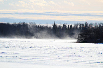 Obraz na płótnie Canvas Blowing and Drifting Snow Across a Frozen Lake