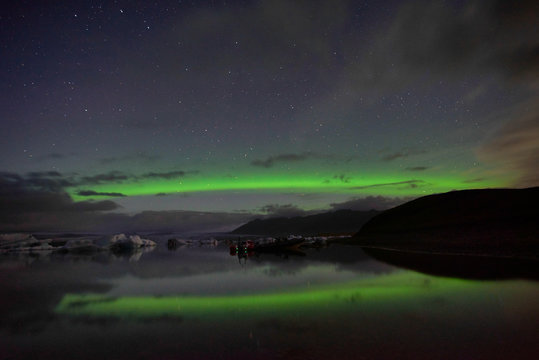 Reflections of aurora borealis over the jokulsarlon lagoon, iceland. image noise due high ISO