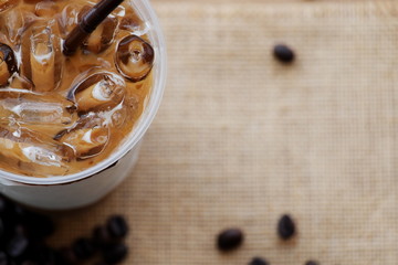 Ice coffee and coffee beans on the brown table.