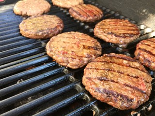 fresh Angus beef hamburgers grilling on the barbecue.