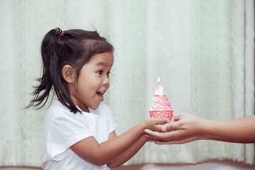 asian little girl having fun to blowing birthday cupcake in vintage color tone