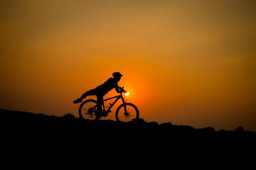 Naklejka na ściany i meble Silhouette of young man cyclist on sunset.