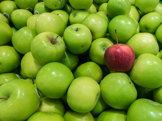 Red apple among green apples
