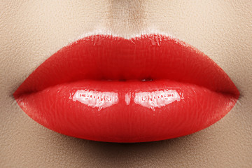 Red juicy lip gloss on lips. Beautiful makeup with best cosmetics. Closeup of mouth with fashion make-up. Part of face