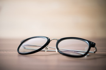 Fototapeta na wymiar black glasses on wooden table. Close-up a black glasses.