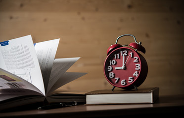 Books and alarm clock on wooden table. Education concept.