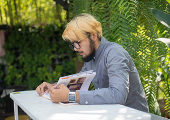 Young hipster beard man reading books in home garden with nature. Education concept.