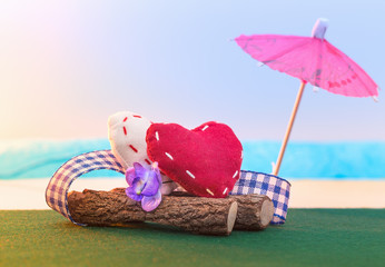 Two textile hearts sit on a log on the seashore. Decline. St. Valentine's Day.