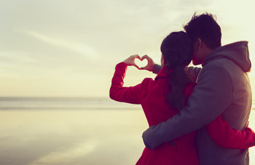 Young couple making a heart shape by hands 
