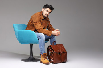 Handsome young man posing. Jacket, boots, jeans, sunglasses.