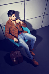 Handsome young man posing. Jacket, boots, jeans, sunglasses.