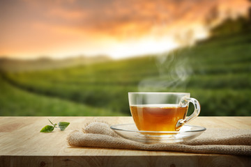 Tea cup with and tea leaf sacking on the wooden table and the tea plantations background
