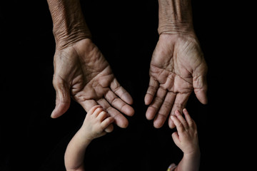 Hand of a young baby touching old hand of the elderly (Soft focus and blurry)