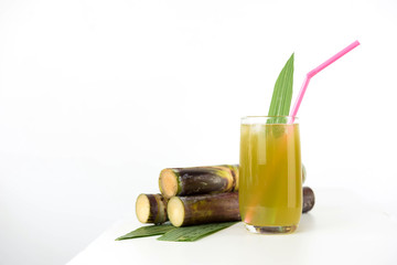 Fresh sugar cane juice in glass on table white background