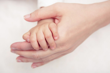 Baby hand gently holding adult's finger (Soft focus and blurry)