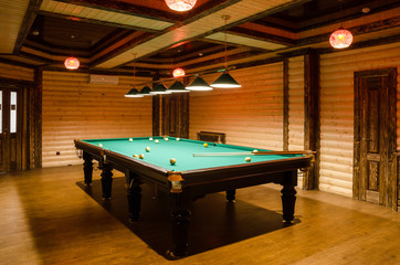 room billiards decorated in dark wood with low lamps, billiard table with green cloth