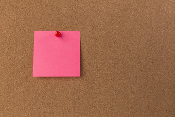 Pink Blank sticky notes red pinned into brown corkboard close up